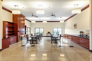 A spacious dining area with multiple tables and chairs, ceiling fans, and pendant lights.