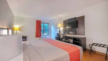 A hotel room with a bed, desk, chair, TV, and two lamps.