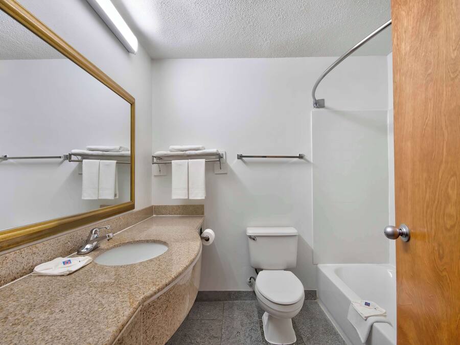 A bathroom with a sink, toilet, and bathtub. There are towels hanging on a rack and a mirror above the sink.