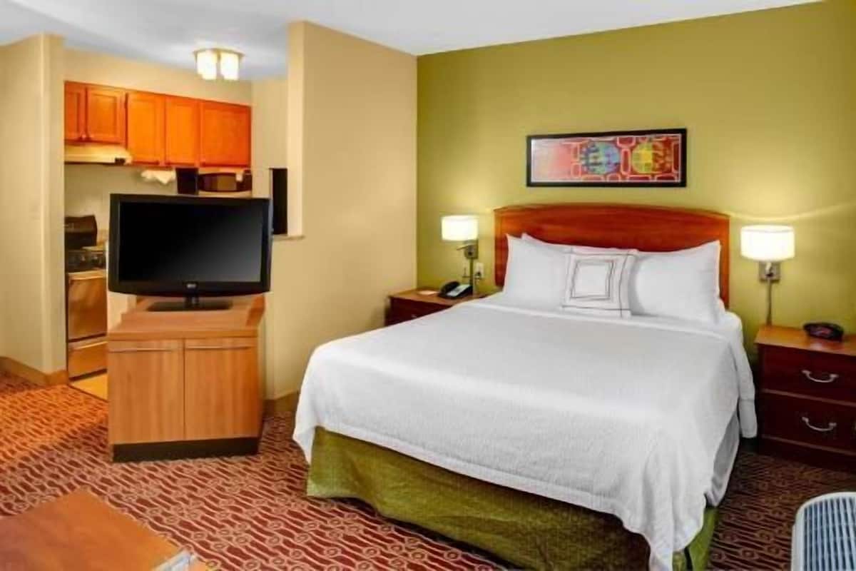 Een hotelkamer met een bed, een televisie, een bureau en een kitchenette.