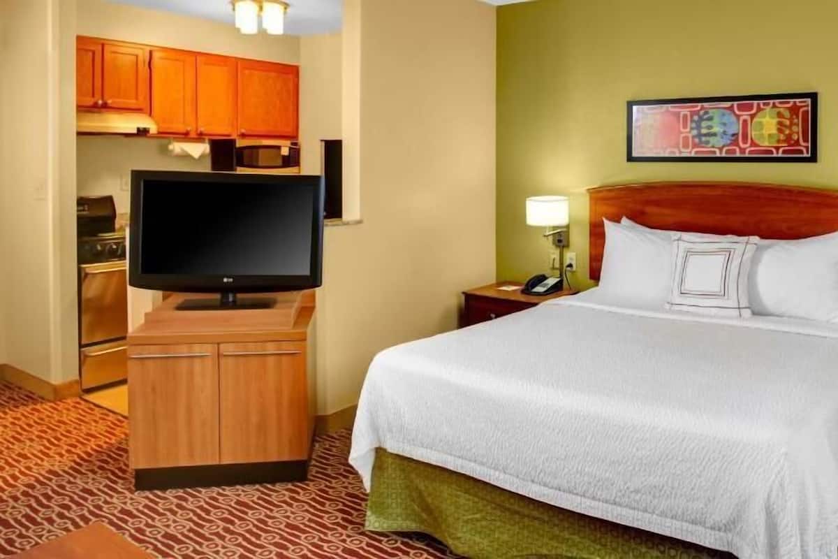 Een hotelkamer met een bed, een televisie, een bureau en een magnetron.