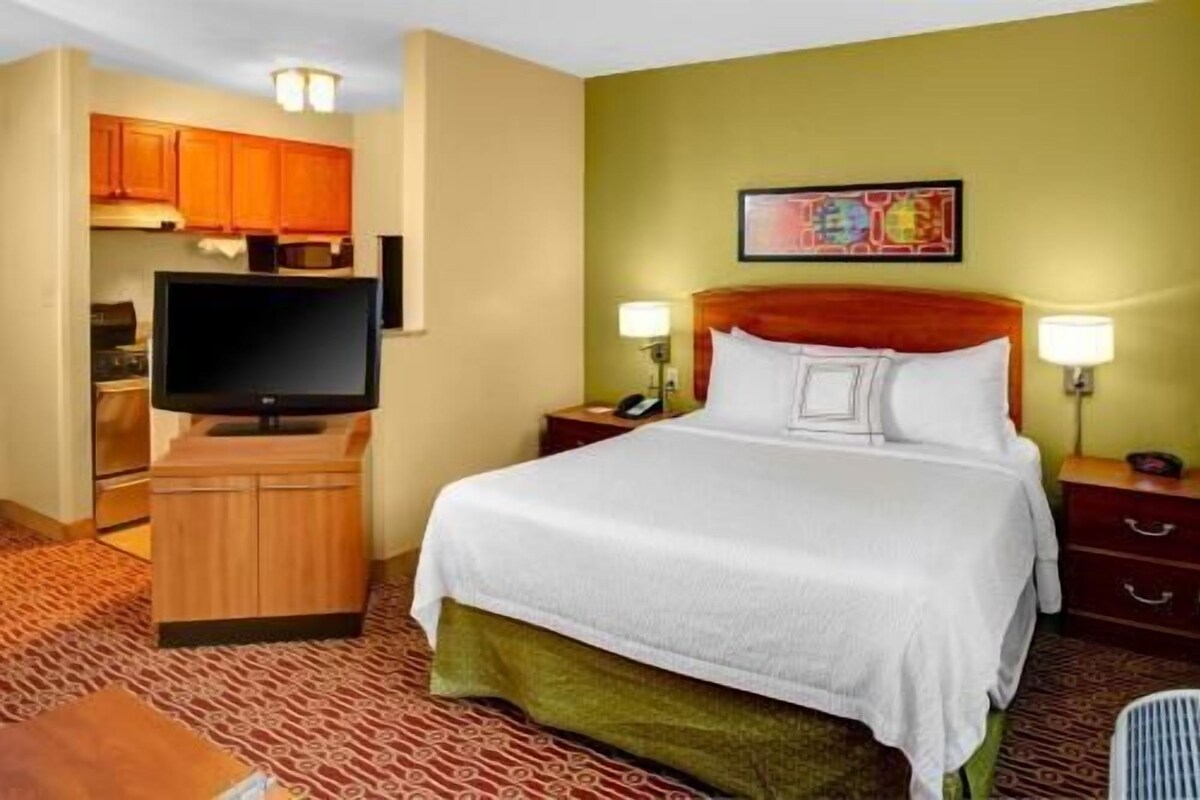 Une chambre d’hôtel équipée d’un lit, d’une télévision, d’un bureau et d’une kitchenette.