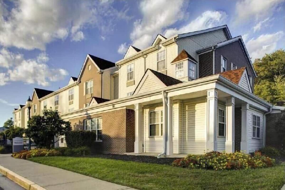 Een rij herenhuizen met een overdekte voortuin, fundering van baksteen en een heldere lucht.