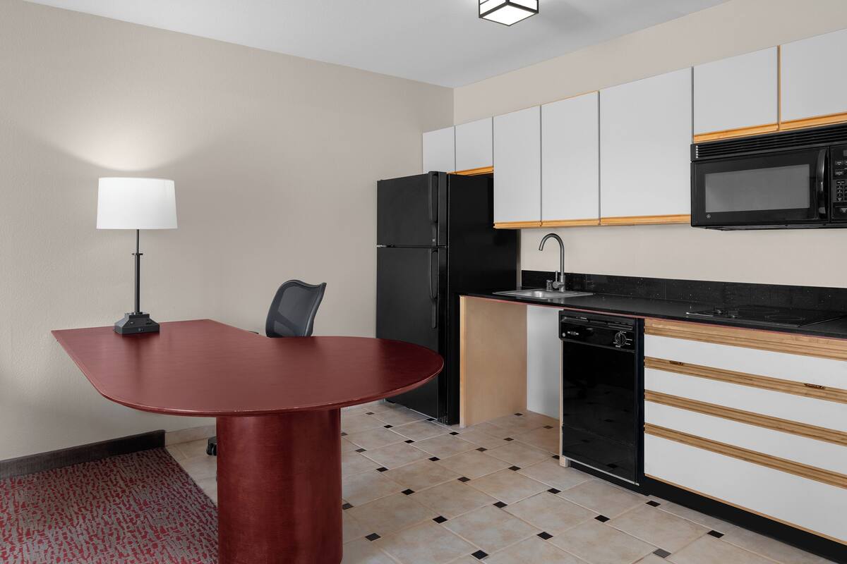 A compact kitchen with a dining table, a refrigerator, a microwave, and a dishwasher.
