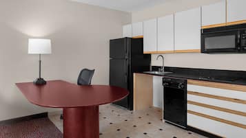 Une cuisine compacte comprenant une table à manger, un réfrigérateur, un four à micro-ondes et un lave-vaisselle.
