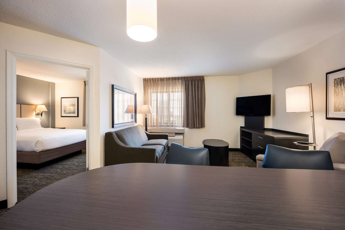A hotel room with a bed, a desk, a TV, and a seating area.