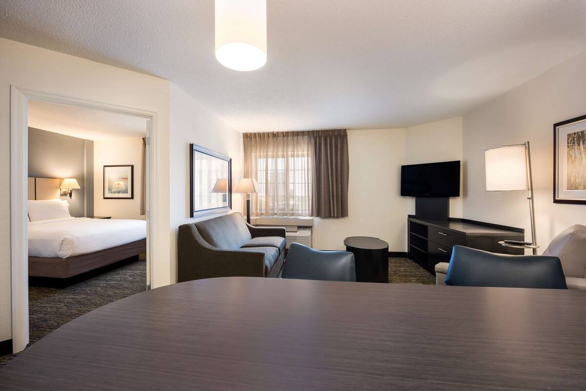 A hotel room with a bed, a desk, a TV, and a seating area.