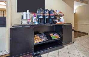 A self-service beverage station with coffee dispensers, a coffee machine, and a tray of pastries.