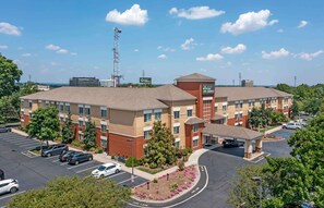 A hotel with a central courtyard, parking lot, and a view of the surrounding area.