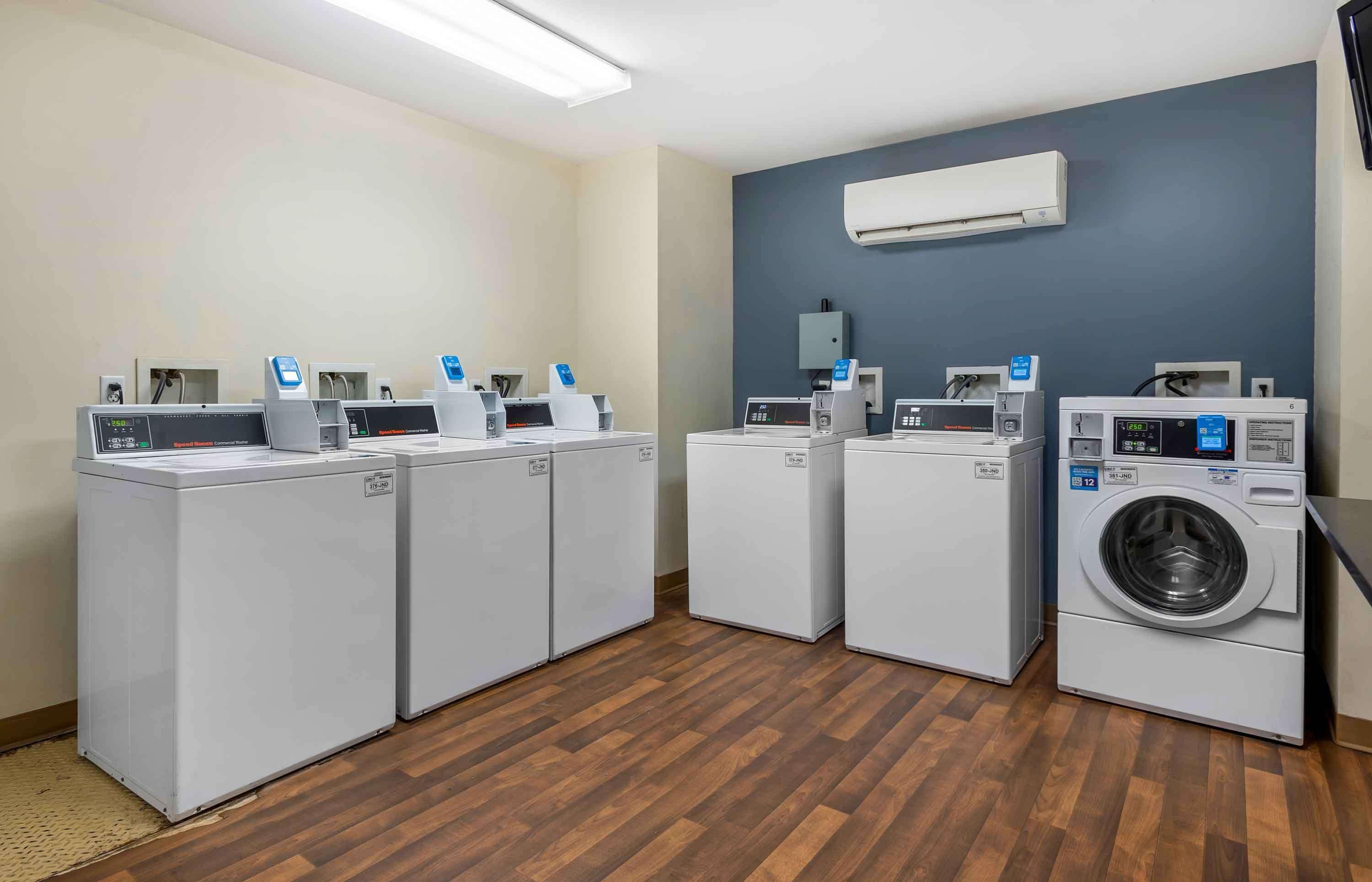 A laundry facility with four washing machines and a dryer, arranged in a row.