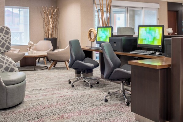 A modern office space with multiple workstations, ergonomic chairs, a large window, and decorative elements like a vase with branches.