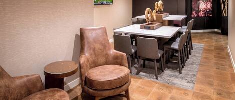 A modern dining area with a large table, multiple chairs, and a television mounted on the wall.