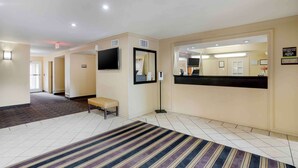 A hotel lobby with a reception desk, a bench, a large mirror, and a striped carpet. - Extended Stay America Suites Memphis Germantown (Memphis)