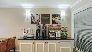 A breakfast bar with coffee makers, a juice dispenser, and a display of breakfast items. - Extended Stay America Suites Memphis Germantown (Memphis)