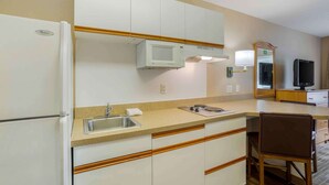 A compact kitchen with a microwave, sink, and wooden cabinets. - Extended Stay America Suites Memphis Germantown (Memphis)
