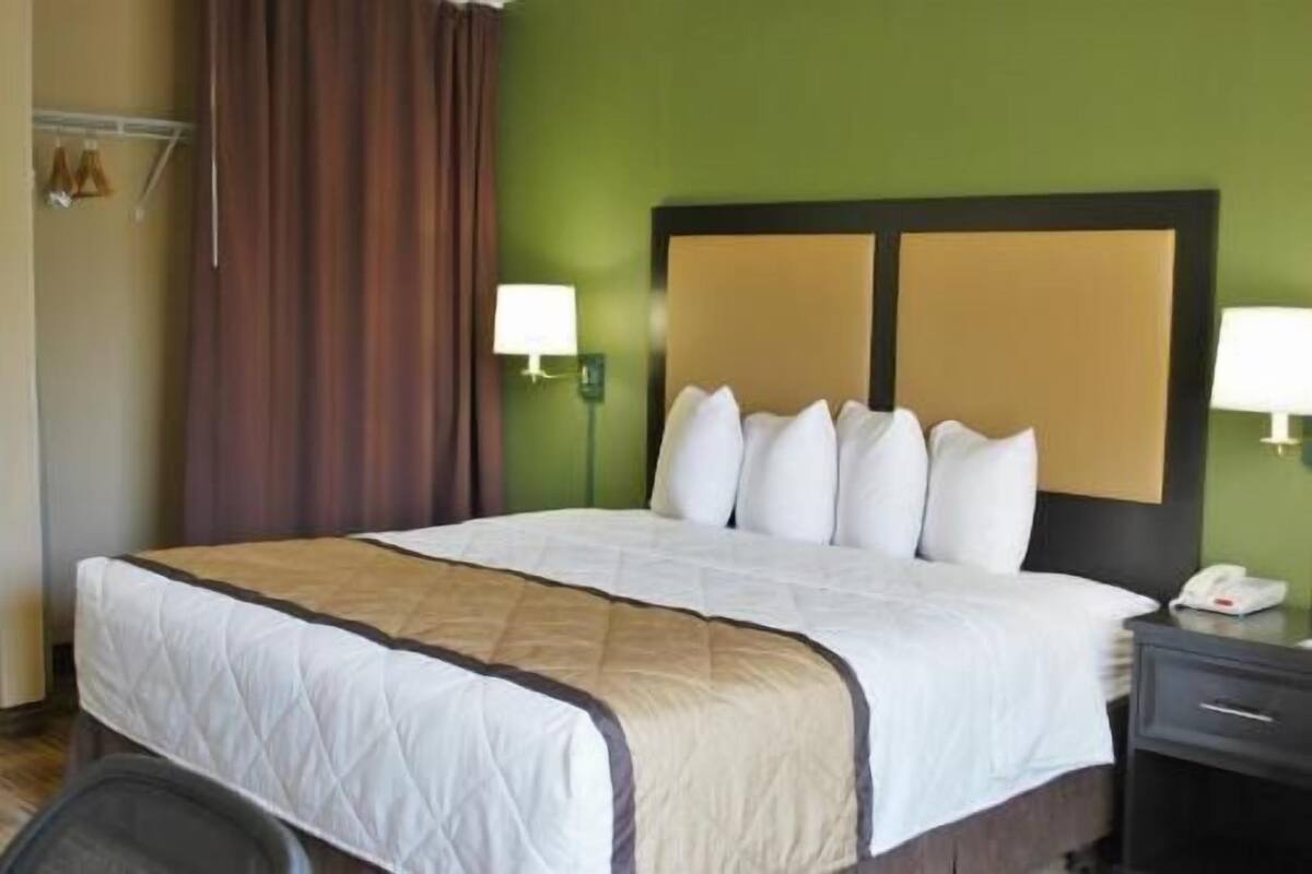 A hotel room with a bed, a nightstand, a lamp, and a telephone.