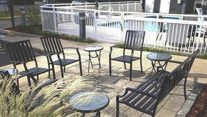 Terrassa exterior amb taules i cadires, una piscina i una zona delimitada per una tanca.