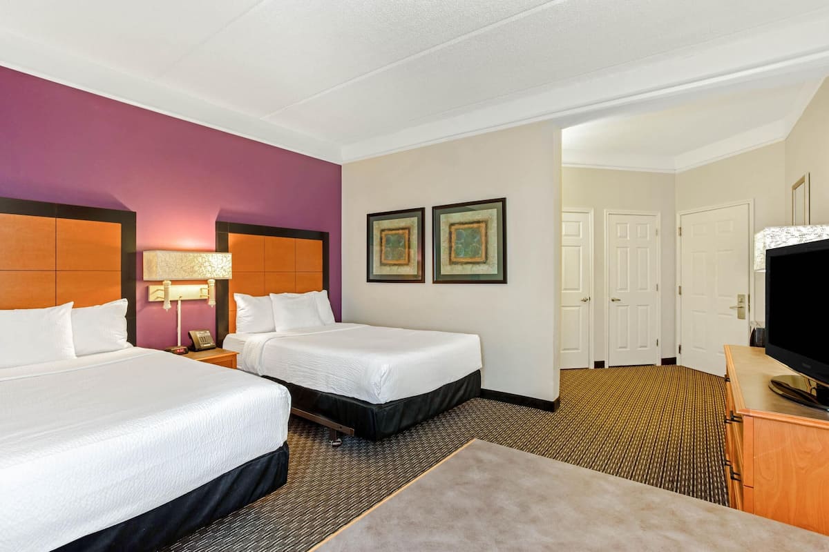 Une chambre d’hôtel avec deux lits, une télévision, un bureau et une chaise.