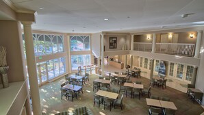 A spacious indoor area with multiple tables and chairs, large windows, and a balcony with railings. - La Quinta Inn & Suites by Wyndham Orlando I Drive/Conv Ctr (Orlando)