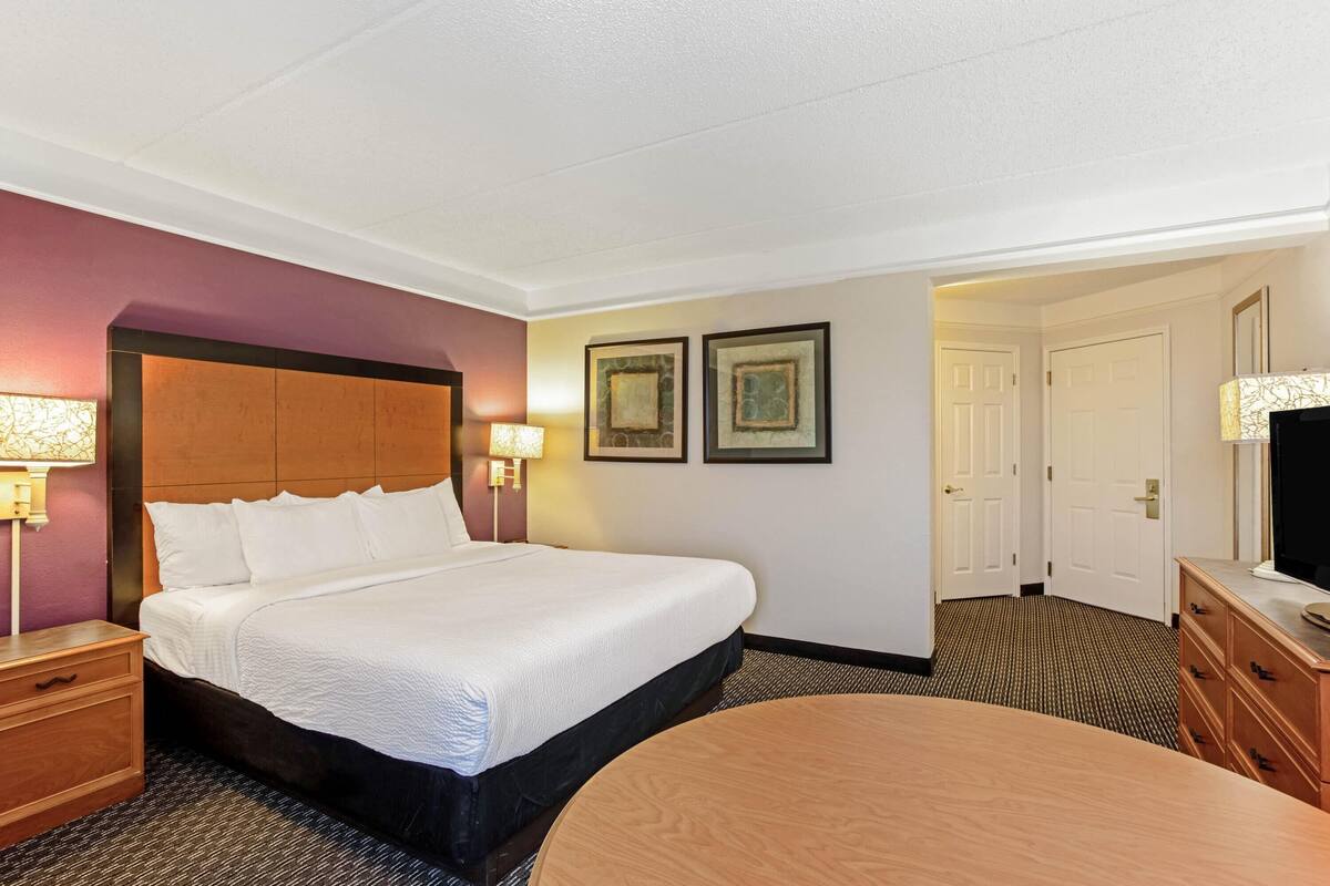 Une chambre d’hôtel avec un grand lit, des tables de chevet, un bureau et un téléviseur.