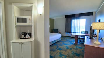A hotel room with a bed, a desk, a chair, a microwave, a lamp, and a small cabinet.