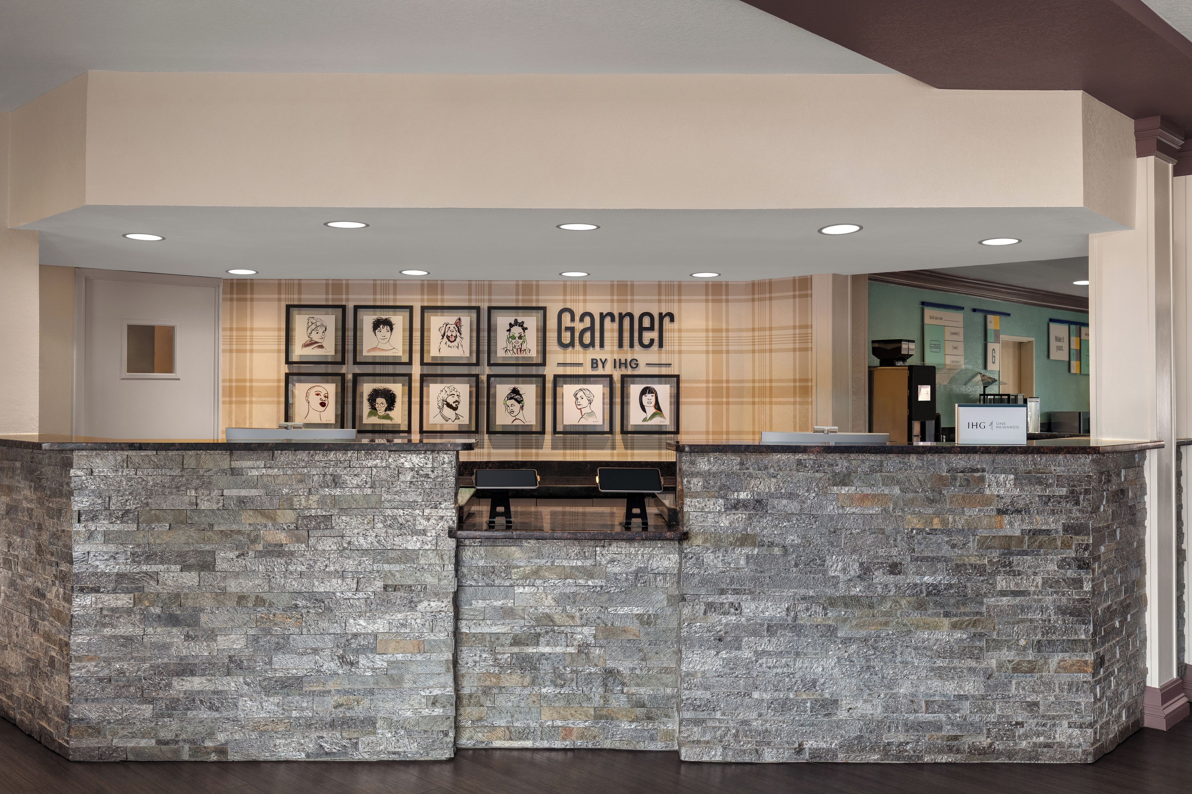 Zona de recepción con mostrador de piedra, obra de arte enmarcada en la pared y un cartel que dice 'Garner by IHG'.