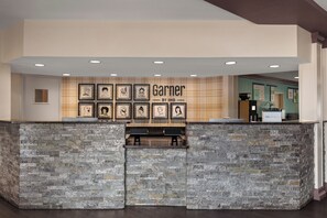 A reception area with a stone counter, framed artwork on the wall, and a sign reading 'Garner by IHG'. - Garner Hotel Denver Airport Area by IHG (Denver)