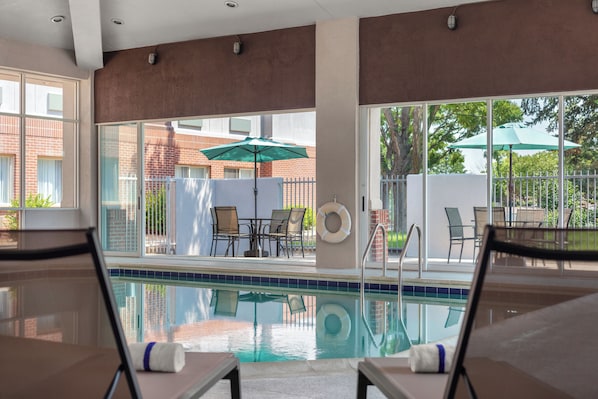 Zona de piscina con sillas de descanso, una piscina y vistas de los edificios circundantes.