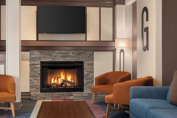 Una sala de estar moderna con chimenea, asientos cómodos y un televisor de pantalla plana montado arriba.