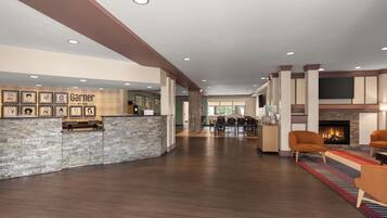 A spacious lobby with a reception desk, framed artwork, a fireplace, and seating area.