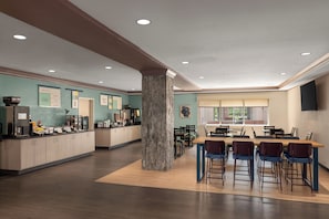 Una cocina moderna con una isla central, barra y zona de comedor con sillas y mesas.