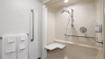 Baño con ducha, barras de apoyo, toallero y retrete.