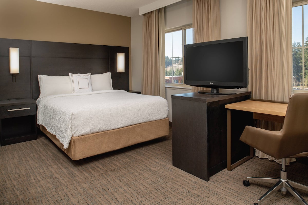 A hotel room with a bed, a desk, a television, and a chair.