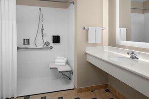 Un baño moderno con cabina de ducha, un lavabo blanco y un espejo grande.