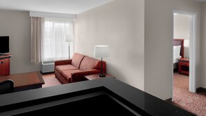 Ein Hotelzimmer mit Schreibtisch, einer roten Couch, einer Lampe und einem Fernseher.