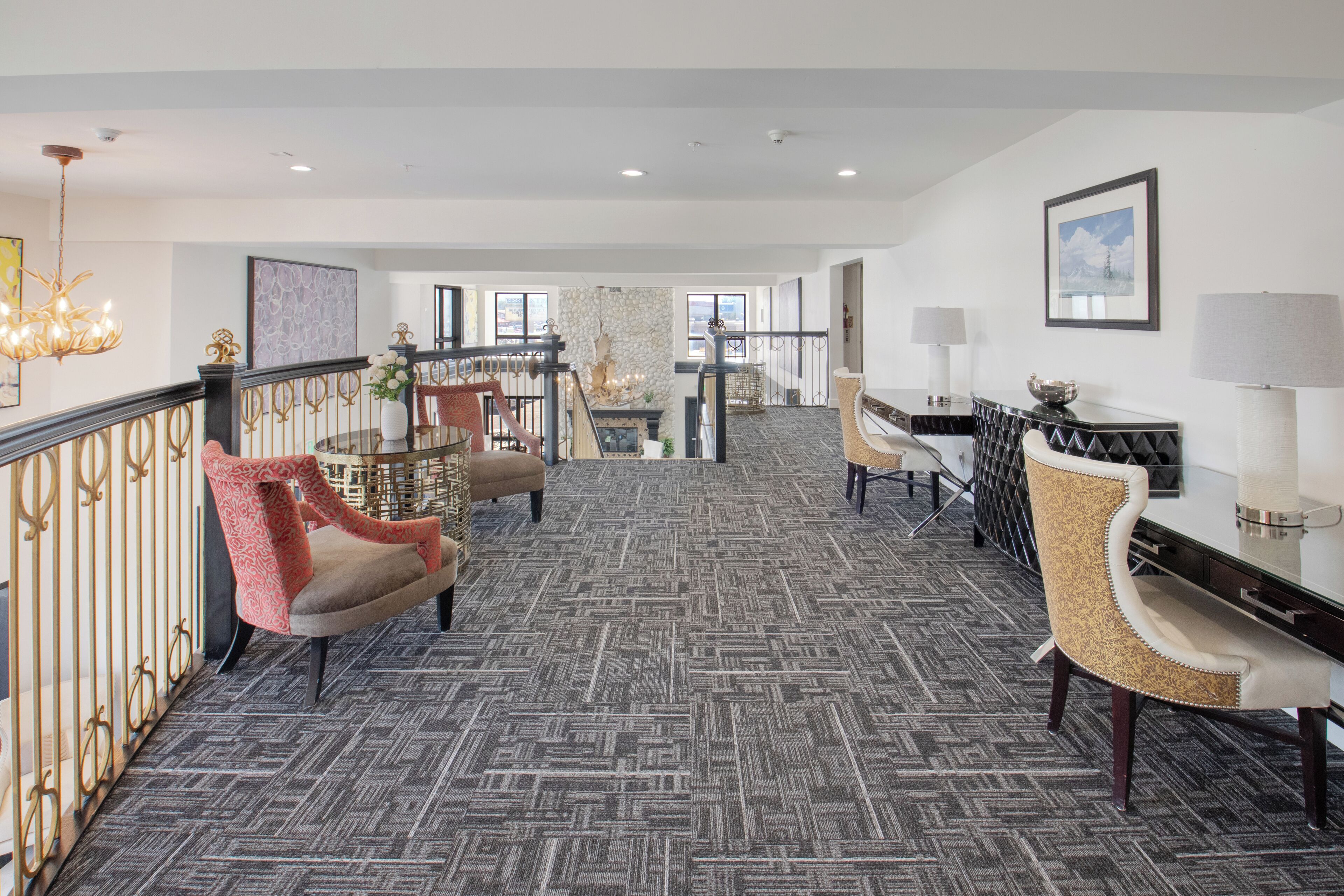 A spacious lobby with a patterned carpet, a staircase, and a seating area with chairs and a table.