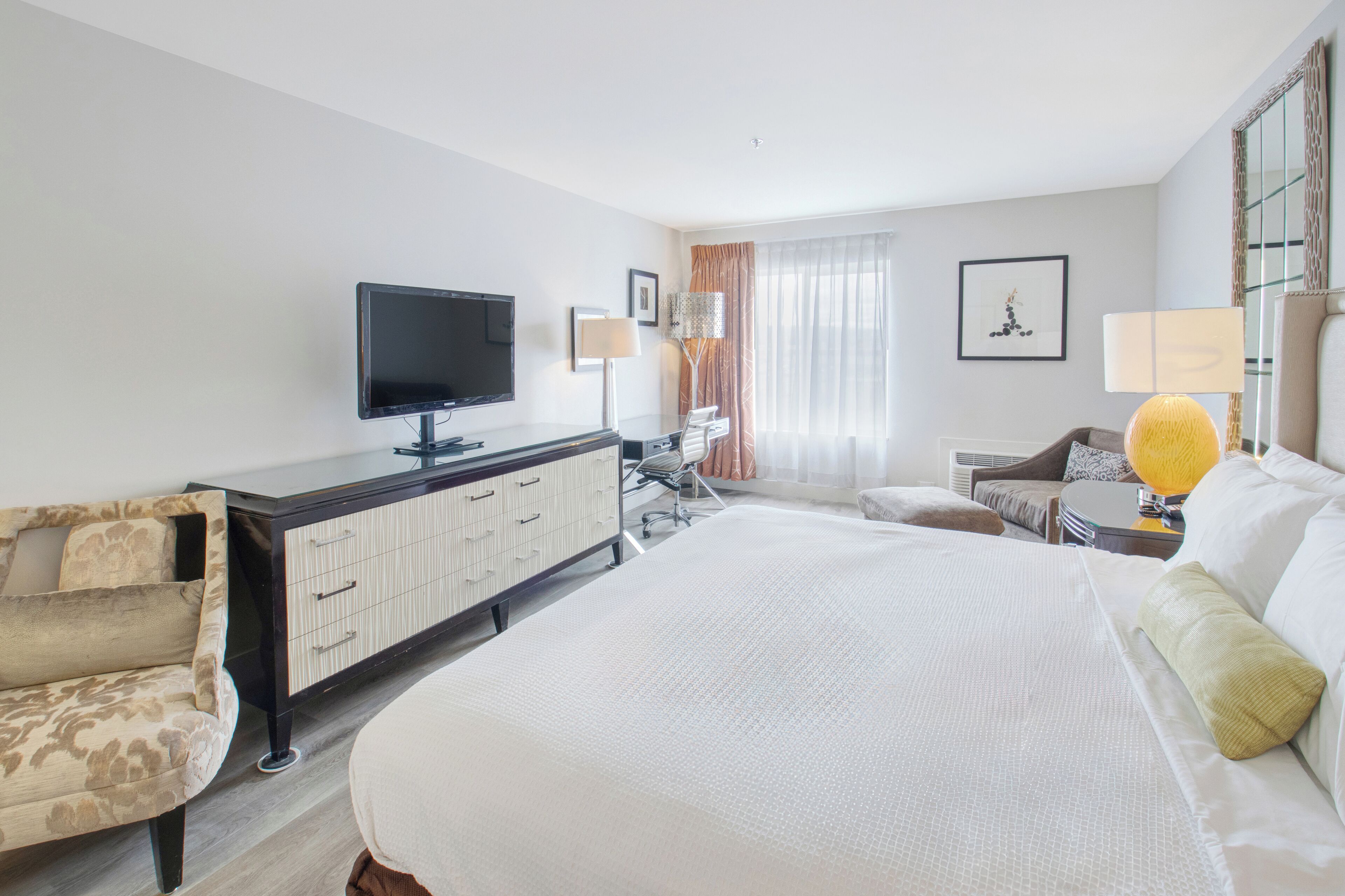 Une chambre d’hôtel avec un grand lit, un téléviseur à écran plat, un bureau avec une chaise, un canapé et une lampe.
