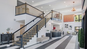 A spacious lobby with a black and white tiled floor, a staircase with black railings, and a reception desk. - Elkotel - The Newest Hotel in Elko (Elko)
