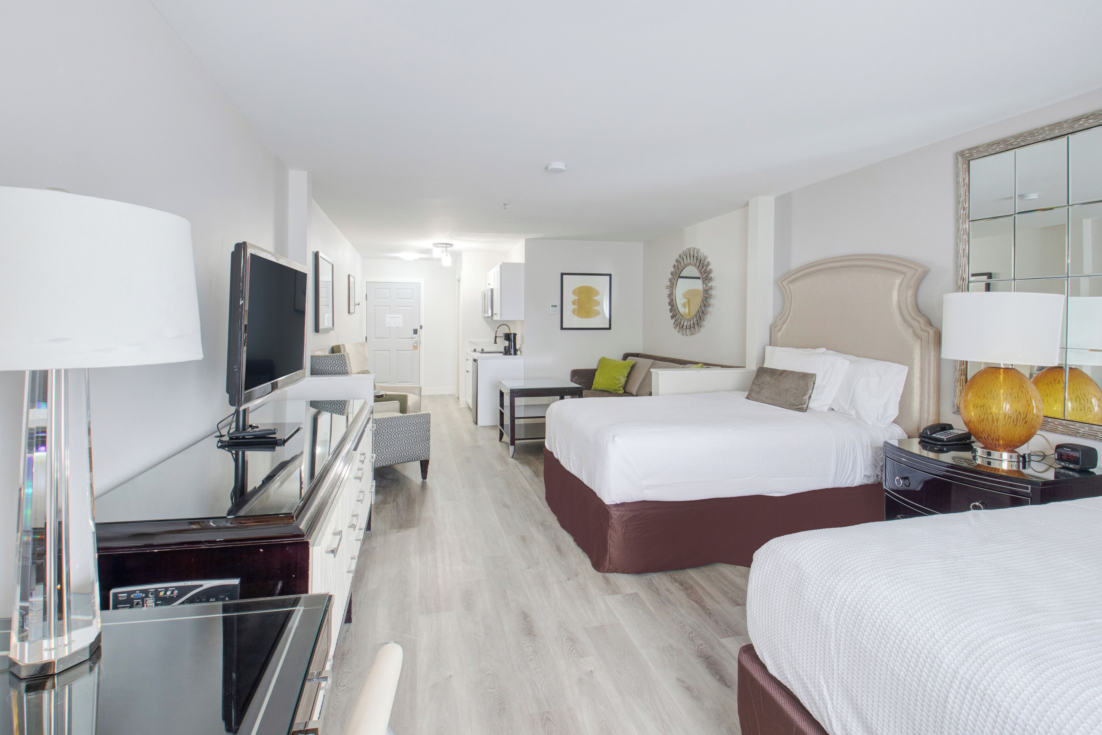 Una habitación de hotel con cama, mesita de noche, lámpara, televisor y un escritorio con silla.