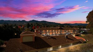 A hotel with multiple buildings, a parking area, and a hilly landscape in the background. - Best Western Willits Inn (Willits)