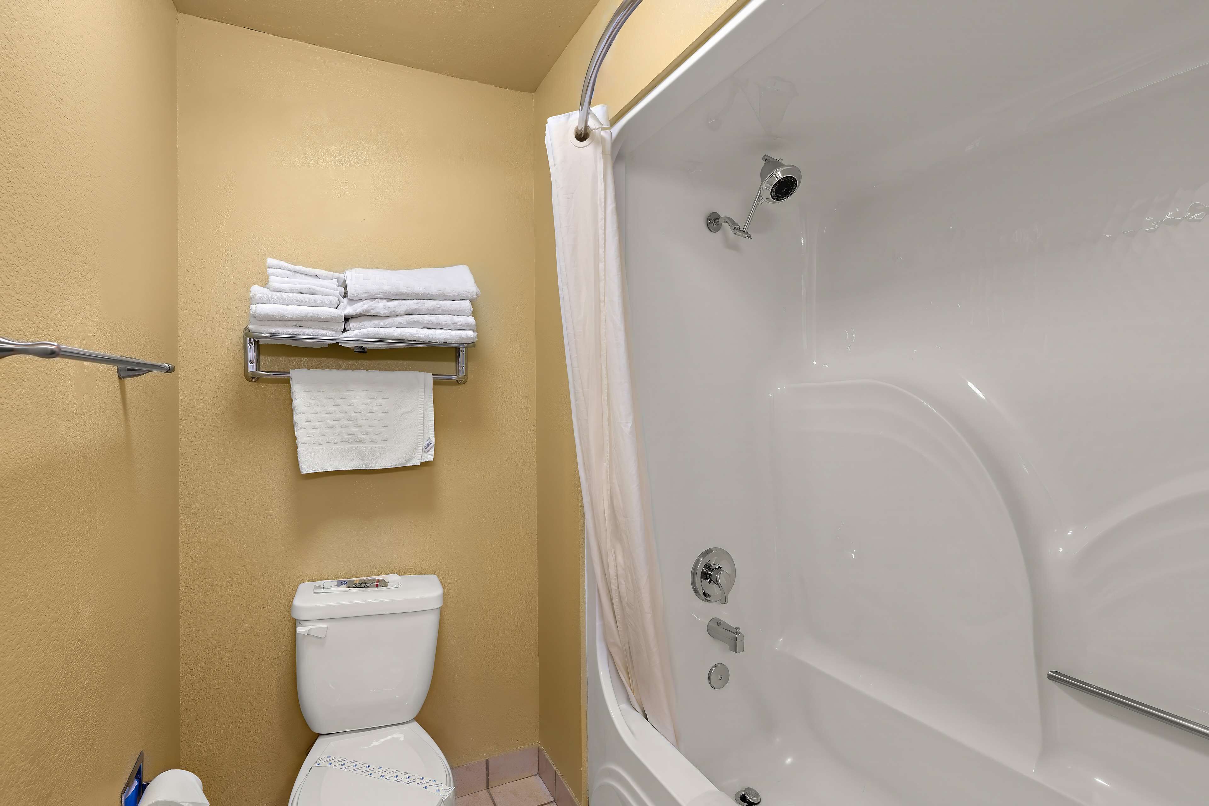 A bathroom with a toilet, a bathtub, and a towel rack with folded towels.