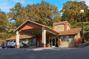 Two-story building with a flat roof and covered parking area, featuring a large window and a door with a glass panel.