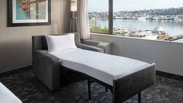 A hotel room with a bed, a view of a harbor, and a framed picture on the wall.