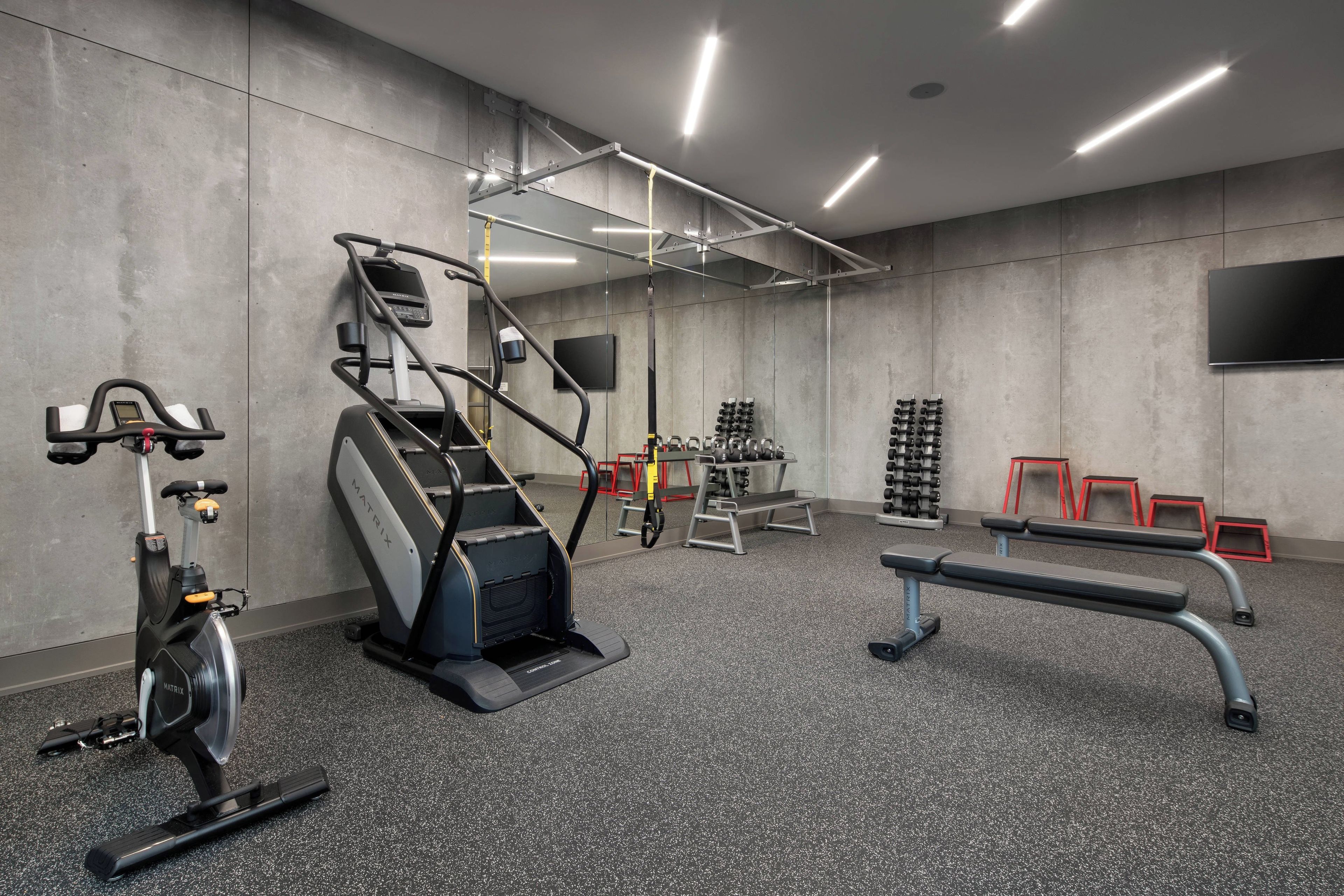 A gym with cardio equipment, weightlifting stations, and benches.