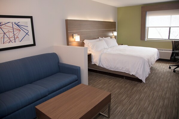 Une chambre d’hôtel avec un lit, un canapé bleu, une table en bois et une œuvre d’art accrochée au mur.