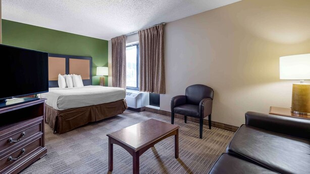 A hotel room with a bed, a television, a desk, a chair, and a sofa. - Extended Stay America Select Suites Dallas Farmers Branch (Dallas)