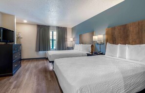 A hotel room with two beds, a TV, a dresser, and a window with curtains. - Extended Stay America Select Suites - Dallas - Lewisville (Lewisville)