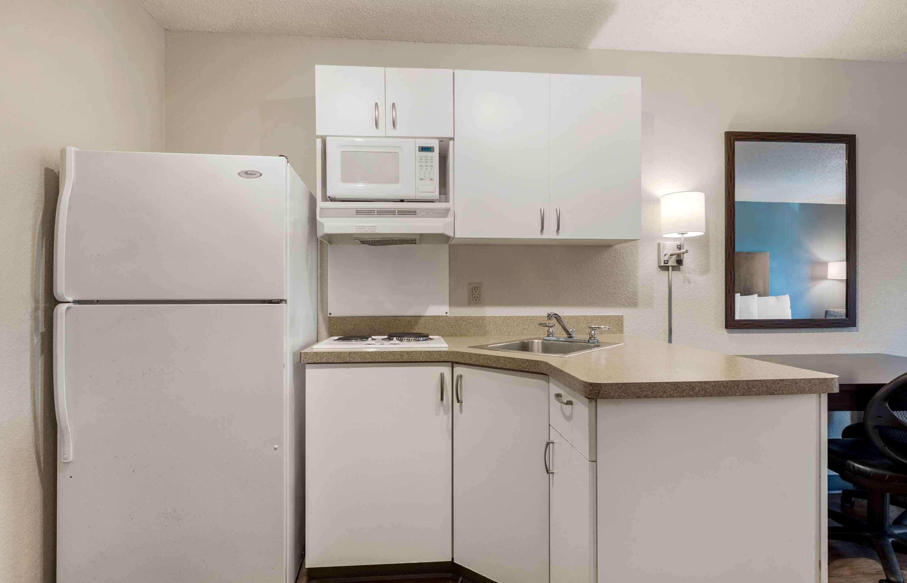 A compact kitchen with a refrigerator, microwave, sink, and cabinets.