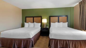 Una habitación de hotel con dos camas, una mesita de noche y una lámpara.