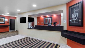 Un espace d’accueil d’hôtel comprenant un comptoir de réception, un téléviseur fixé au mur et un trophée encadré accroché au mur.